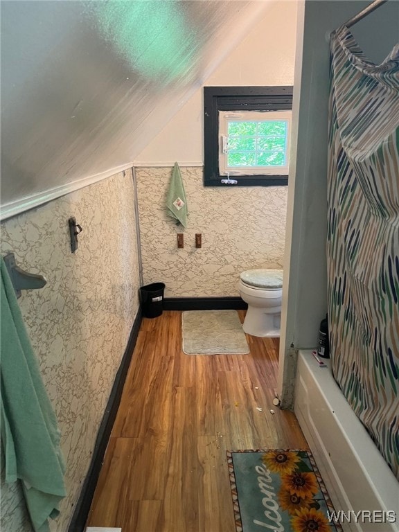 bathroom featuring shower / bath combo, lofted ceiling, hardwood / wood-style floors, and toilet