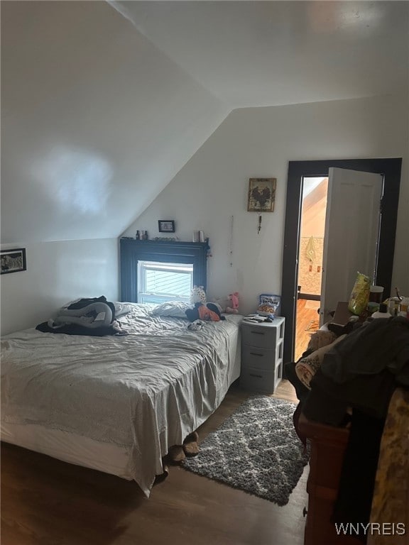 bedroom featuring hardwood / wood-style flooring, lofted ceiling, and ensuite bath