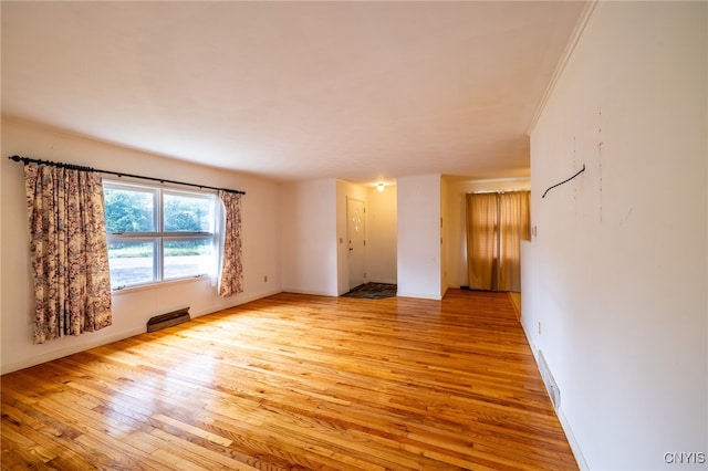 empty room with light hardwood / wood-style floors and ornamental molding