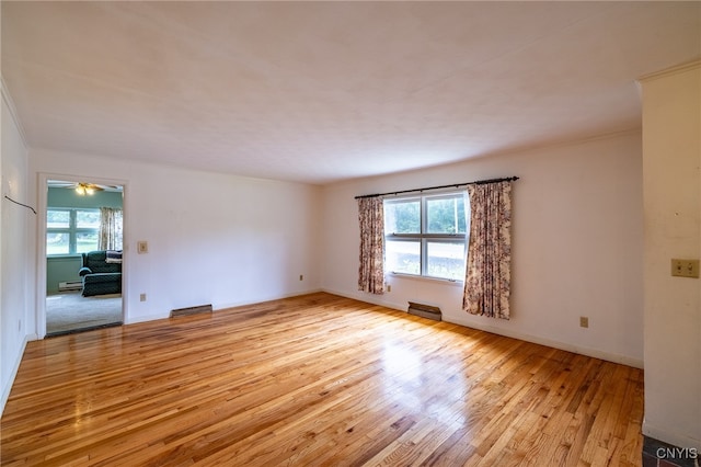 spare room with light hardwood / wood-style flooring, ceiling fan, baseboard heating, and a healthy amount of sunlight