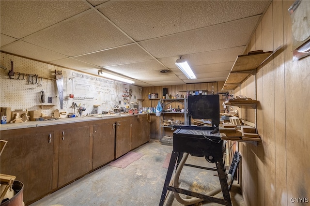 interior space with wood walls, a workshop area, and a paneled ceiling