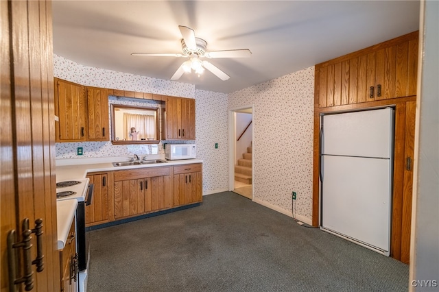 kitchen with white appliances, dark carpet, sink, and ceiling fan