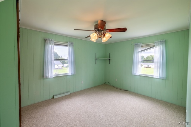 empty room with carpet flooring, a baseboard heating unit, and ceiling fan