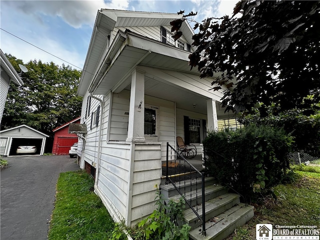 bungalow-style home with covered porch, an outdoor structure, and a garage