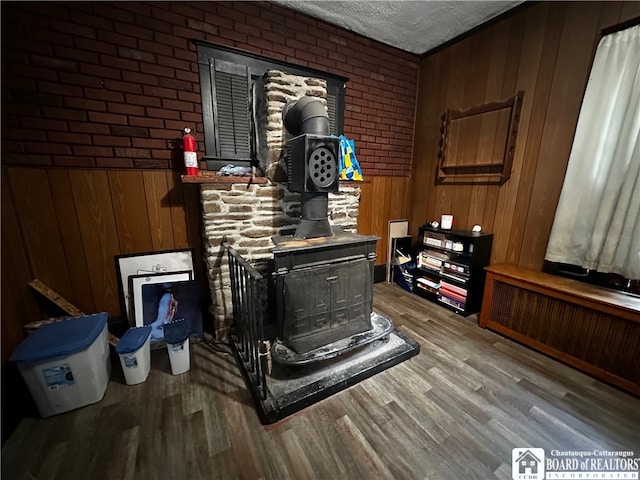 details featuring radiator heating unit, a wood stove, a textured ceiling, wood-type flooring, and wooden walls