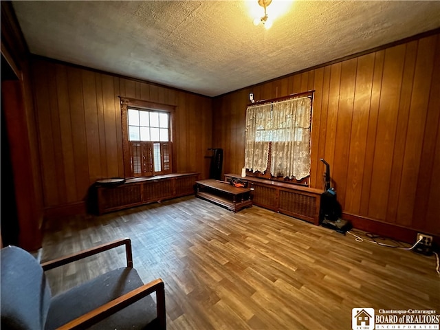 miscellaneous room with hardwood / wood-style flooring, wood walls, and a textured ceiling