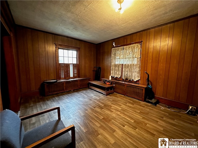 interior space featuring a textured ceiling, wood walls, and hardwood / wood-style flooring