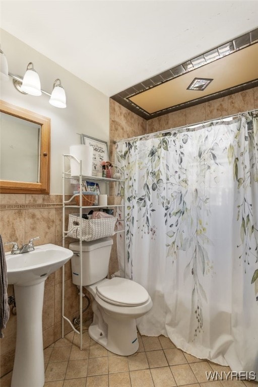 bathroom with a shower with curtain, tile walls, tile patterned flooring, and toilet