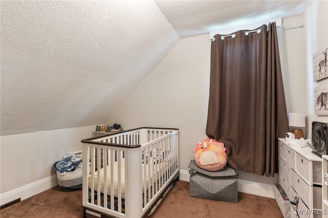 bedroom featuring vaulted ceiling, a textured ceiling, a crib, and carpet floors