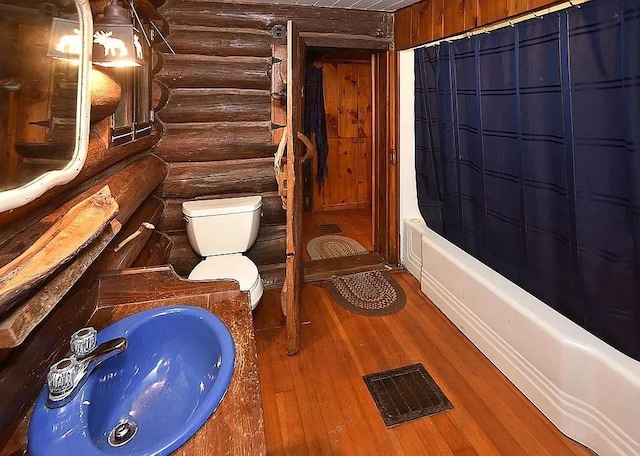 8578 County Road 49, Rushford, NY 14717 - full bathroom featuring log walls, toilet, wood finished floors, and shower / bath combination with curtain