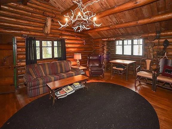 8578 County Road 49, Rushford, NY 14717 - living area with wooden ceiling, wood finished floors, a chandelier, log walls, and plenty of natural light