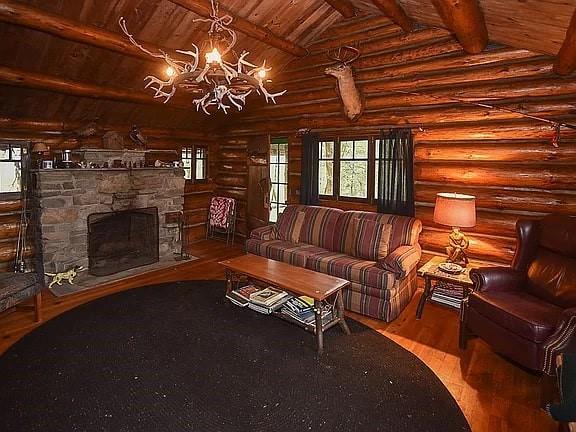 8578 County Road 49, Rushford, NY 14717 - living area featuring wooden ceiling, log walls, a chandelier, wood finished floors, and healthy amount of natural light