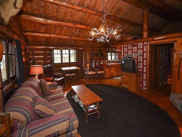 8578 County Road 49, Rushford, NY 14717 - living area featuring log walls, wood ceiling, a chandelier, and wood finished floors