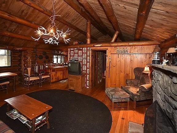 8578 County Road 49, Rushford, NY 14717 - living area with wood ceiling, rustic walls, a chandelier, wood-type flooring, and healthy amount of natural light
