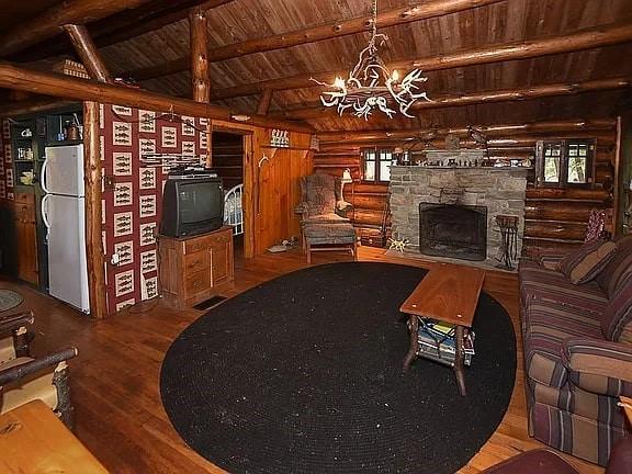8578 County Road 49, Rushford, NY 14717 - unfurnished living room with wooden ceiling, rustic walls, wood finished floors, a chandelier, and plenty of natural light