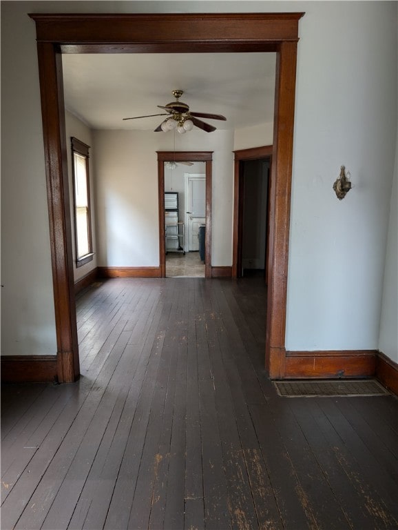 unfurnished living room with dark hardwood / wood-style flooring and ceiling fan