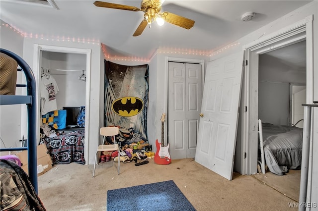 carpeted bedroom featuring ceiling fan and two closets