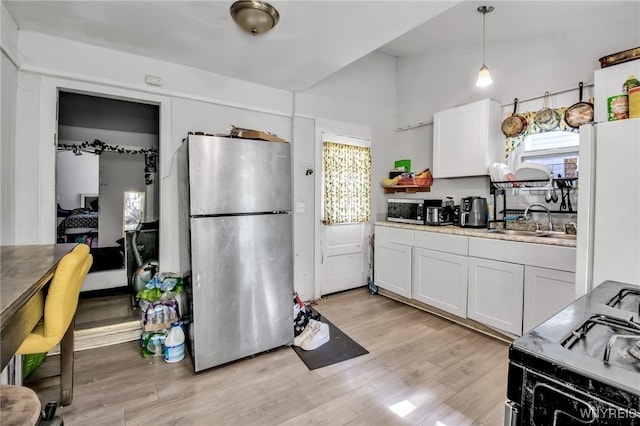 kitchen with light hardwood / wood-style floors, sink, lofted ceiling, appliances with stainless steel finishes, and white cabinetry