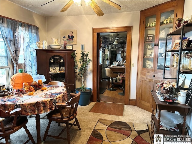 carpeted dining area with a textured ceiling and ceiling fan