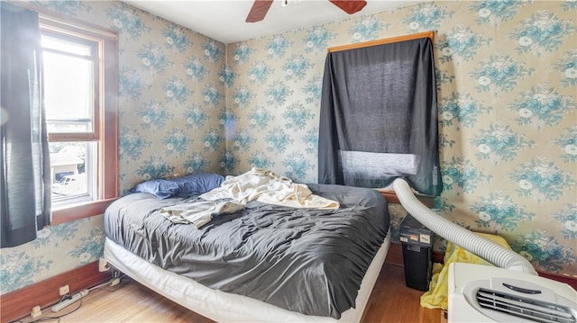 bedroom with multiple windows, ceiling fan, and hardwood / wood-style floors