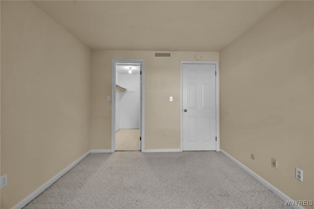 unfurnished bedroom with light carpet, a closet, and a spacious closet