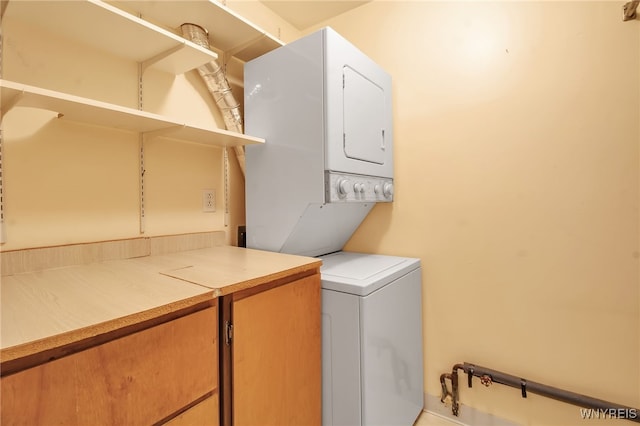 laundry room with stacked washer / drying machine and cabinets