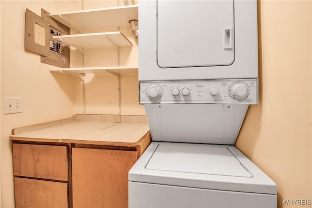 clothes washing area featuring cabinets and stacked washer and dryer