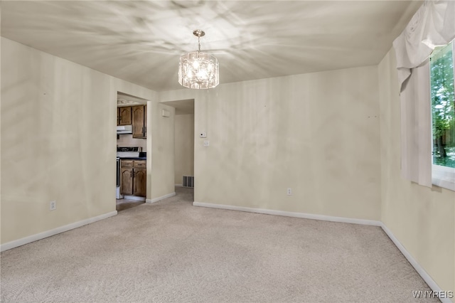 carpeted empty room with an inviting chandelier