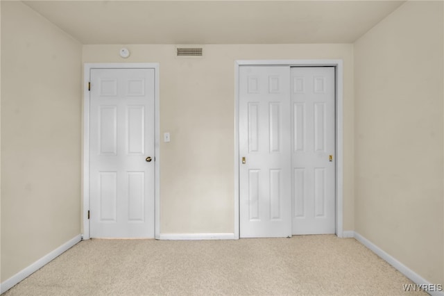 unfurnished bedroom with light carpet and a closet