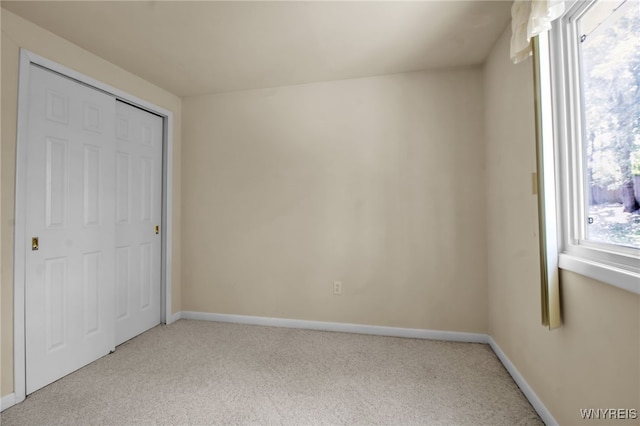 unfurnished bedroom featuring light colored carpet and a closet