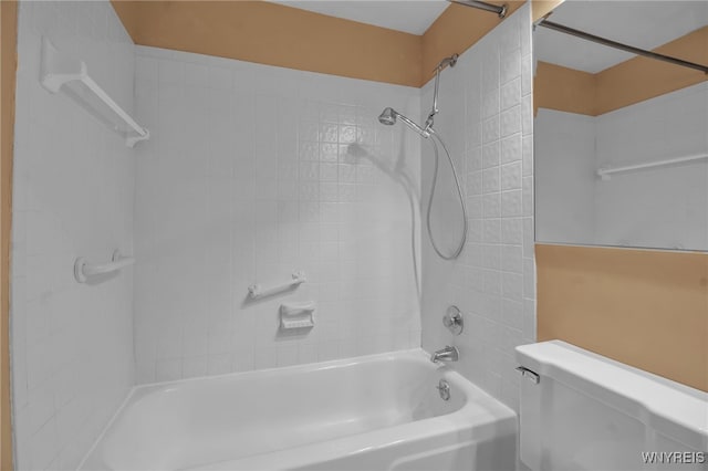 bathroom with tiled shower / bath combo and toilet