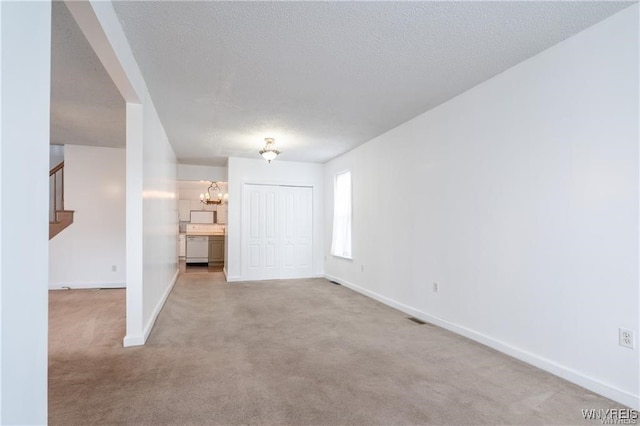 unfurnished room featuring light carpet, a chandelier, and a textured ceiling