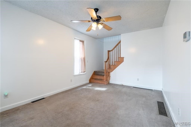 carpeted spare room featuring ceiling fan and a textured ceiling