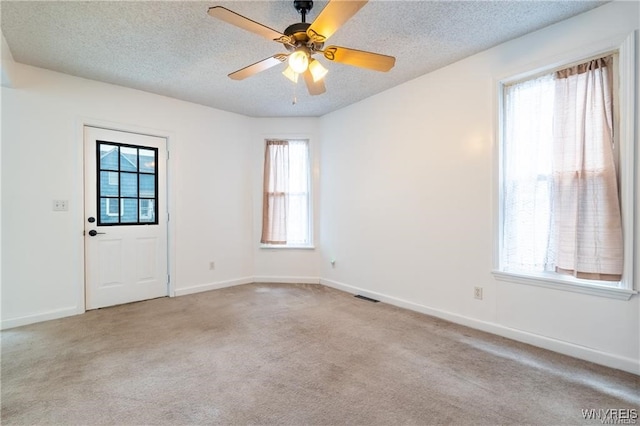 unfurnished room with ceiling fan, light carpet, and a textured ceiling