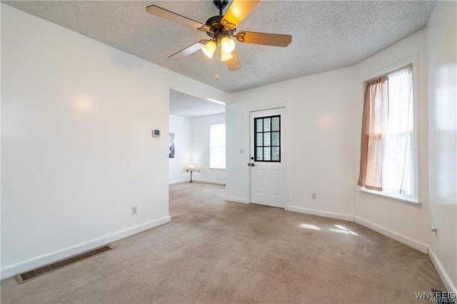 carpeted empty room with ceiling fan and a textured ceiling