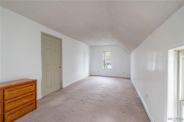 bonus room with vaulted ceiling, light carpet, and a textured ceiling