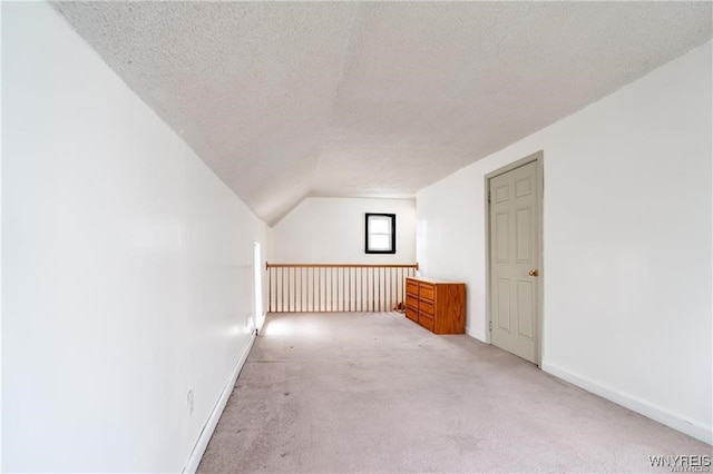 additional living space with light colored carpet, lofted ceiling, and a textured ceiling