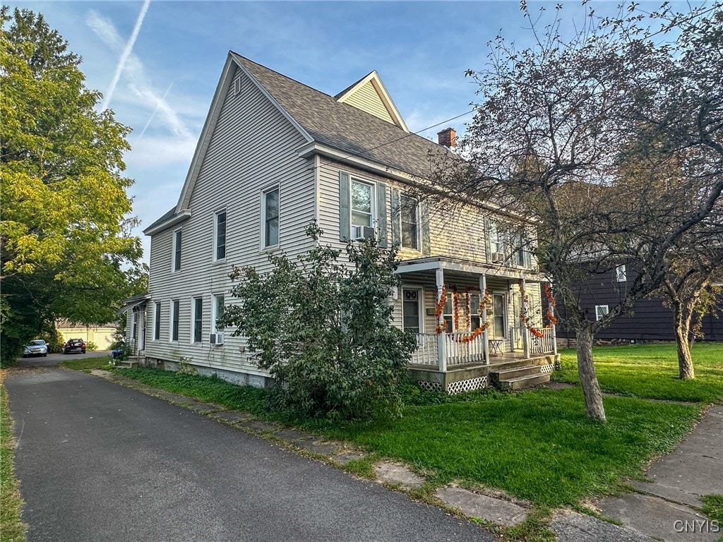 view of side of property with a porch and a lawn