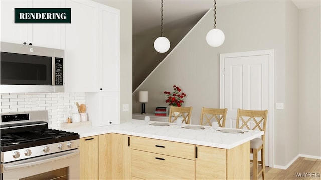 kitchen featuring kitchen peninsula, a breakfast bar, appliances with stainless steel finishes, light brown cabinets, and pendant lighting