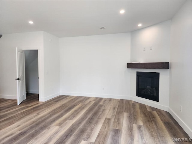 28 Glen Burn Trl, Ellicottville, NY 14731 - unfurnished living room with wood finished floors, recessed lighting, a glass covered fireplace, and baseboards