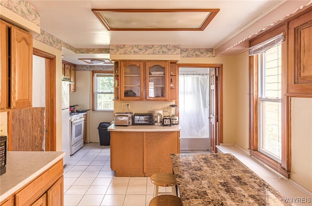 kitchen with light tile patterned floors, a kitchen bar, and white range with gas stovetop