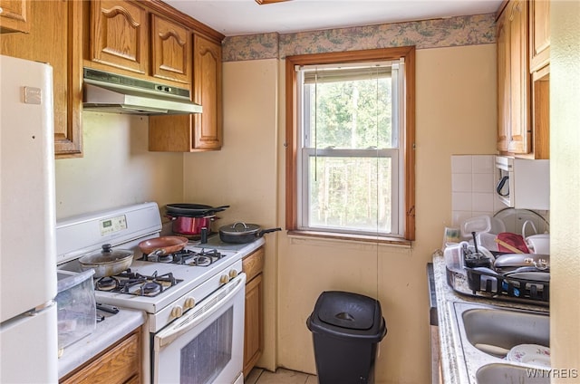 kitchen with sink, white appliances, and tasteful backsplash