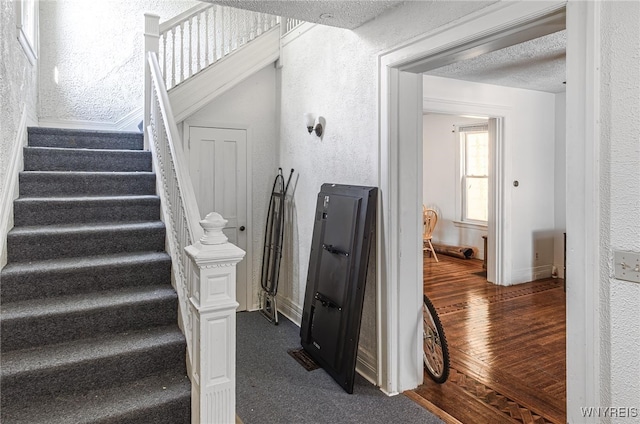 stairway featuring a textured ceiling and wood-type flooring