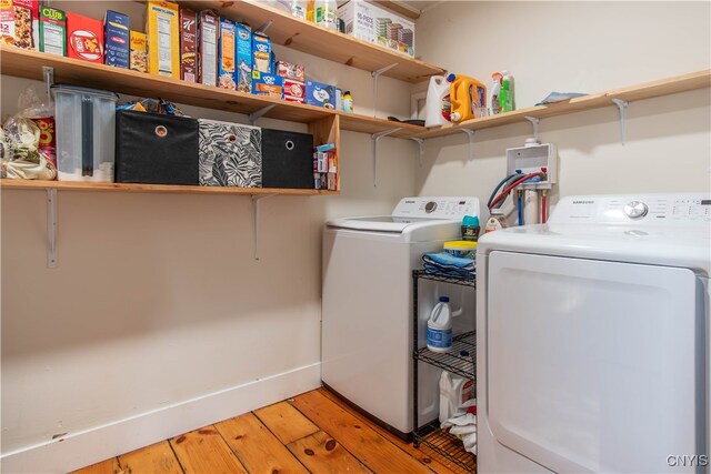 clothes washing area with hardwood / wood-style floors and washer and dryer