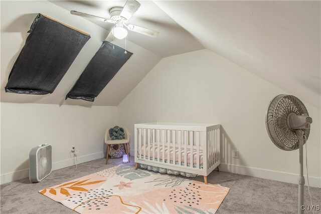 carpeted bedroom featuring a crib, vaulted ceiling, and ceiling fan