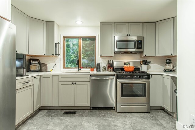 kitchen with gray cabinetry, sink, and stainless steel appliances