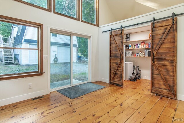 entryway with a barn door, a towering ceiling, light hardwood / wood-style flooring, and washing machine and clothes dryer