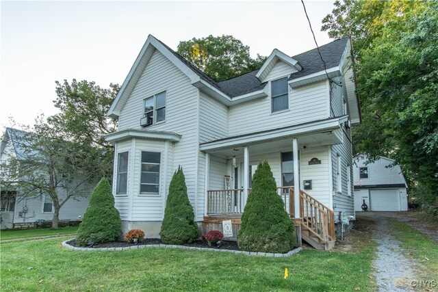 view of front of property featuring covered porch, a front yard, an outbuilding, and a garage