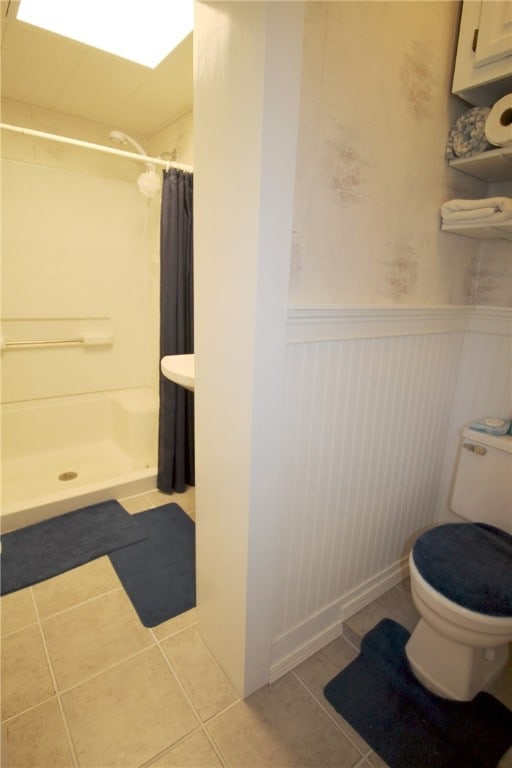 bathroom featuring walk in shower, tile patterned flooring, and toilet