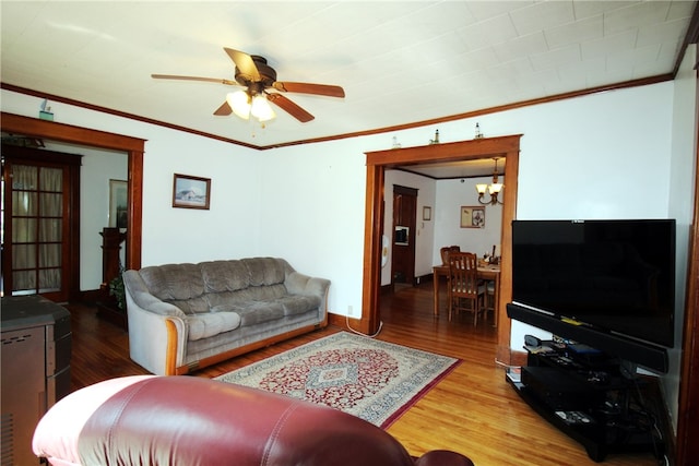 living room with ornamental molding, ceiling fan with notable chandelier, and hardwood / wood-style floors